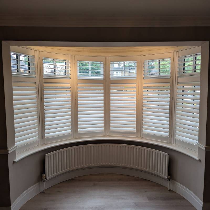Full-height bay window shutters in white.