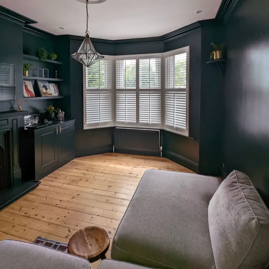 White shutters in a living room with navy painted walls.